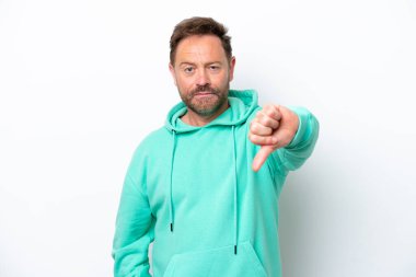 Beyaz arka planda izole edilmiş orta yaşlı beyaz bir adam negatif ifadeyle baş parmağını aşağı gösteriyor.
