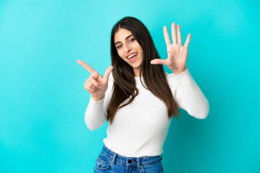 Mavi arka planda izole edilmiş beyaz kadın yediyi parmaklarıyla sayıyor.