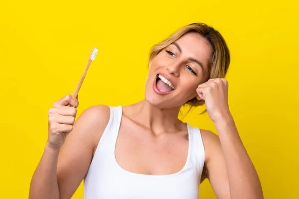 Młoda Urugwajska Kobieta Myje Zęby Odizolowane Żółtym Tle Świętując Zwycięstwo — Zdjęcie stockowe