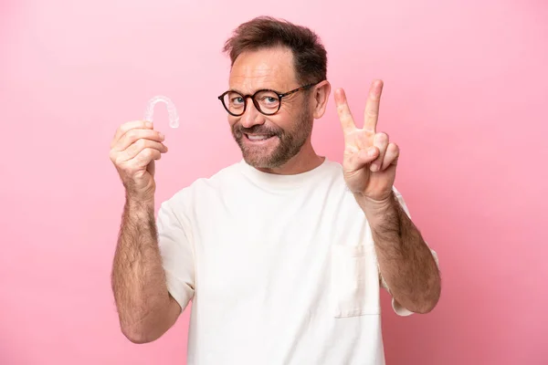 Uomo Mezza Età Tenendo Bretelle Invisibili Isolato Sfondo Rosa Sorridente — Foto Stock