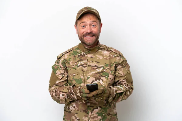Military man isolated on white background sending a message with the mobile