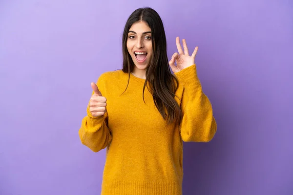 年轻的高加索女人 在紫色背景上被隔离 露出可控的手势和竖起大拇指的姿势 — 图库照片
