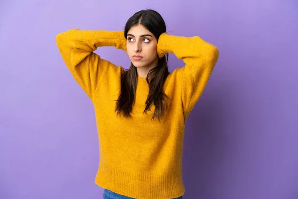 Young caucasian woman isolated on purple background frustrated and covering ears