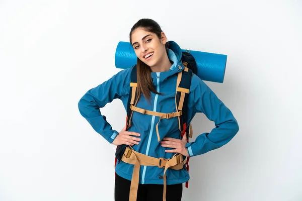年轻的登山者 背着一个大背包 背对孤立的背景 双手叉腰 面带微笑 — 图库照片