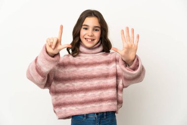 Beyaz arka planda izole edilmiş küçük beyaz kız yediyi parmaklarıyla sayıyor.