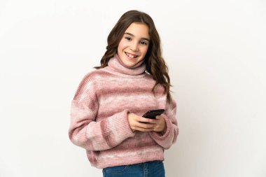 Beyaz arka planda izole edilmiş küçük beyaz kız cep telefonuyla bir mesaj gönderiyor.
