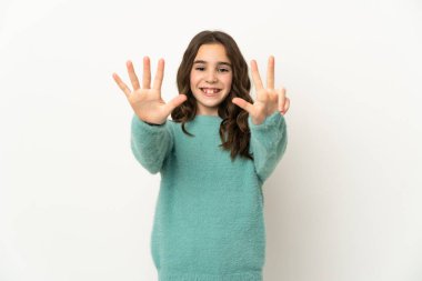 Beyaz arka planda izole edilmiş küçük beyaz kız parmaklarıyla sekiz sayıyor.