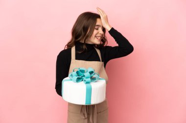 Pembe arka planda büyük bir pasta tutan küçük pasta şefi bir şey fark etti ve çözüme niyetlendi.