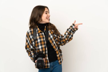 Arka planda izole edilmiş küçük fotoğrafçı kız parmağını yana doğru uzattı ve bir ürün sundu.
