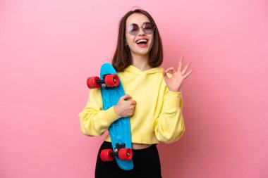 Genç Ukraynalı bir kadın pembe arka planda izole edilmiş ve paten kayıyor.