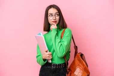 Genç öğrenci Ukraynalı kadın pembe arka planda izole edilmiş ve araştırılıyor.