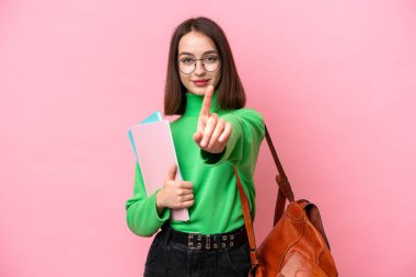 Pembe arka planda izole edilmiş genç Ukraynalı kadın parmağını kaldırıyor ve gösteriyor.