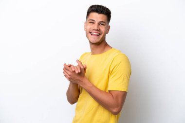 Beyaz arka planda izole edilmiş genç beyaz adam alkışlıyor.