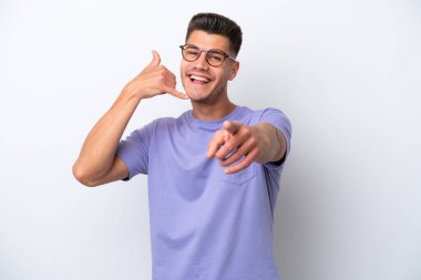 Beyaz arka planda izole edilmiş genç beyaz bir adam telefon jesti yapıyor ve ön tarafı işaret ediyor.
