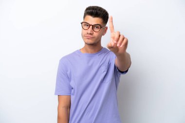 Beyaz arka planda izole edilmiş beyaz tenli genç adam ciddi bir ifadeye sahip birini sayıyor.