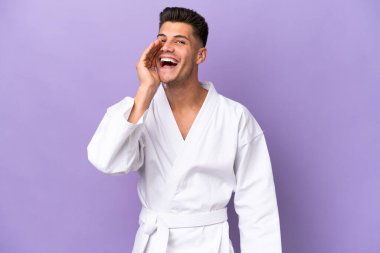 Mor arka planda karate yapan genç beyaz bir adam ağzı açık bağırıyor.