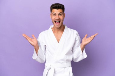 Kafkasyalı genç bir adam mor arka planda karate yapıyor. Yüzünde şok ifadesi var.