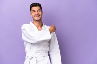 Mor arka planda karate yapan genç beyaz adam geriye bakıyor.