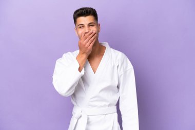 Mor arka planda karate yapan genç beyaz adam mutlu ve gülümsüyor.