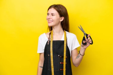 Sarı arka planda izole edilmiş genç terzi İngiliz kadın.