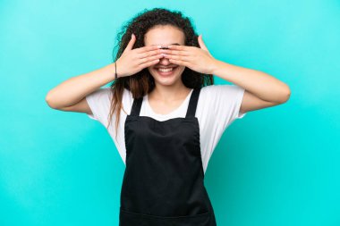 Restoran garsonu Arap kadın, mavi arka planda tek başına, gözleri elleriyle kapatıyor.