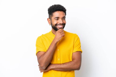 Genç Brezilyalı bir adam beyaz arka planda izole edilmiş, yana bakıyor ve gülümsüyor.