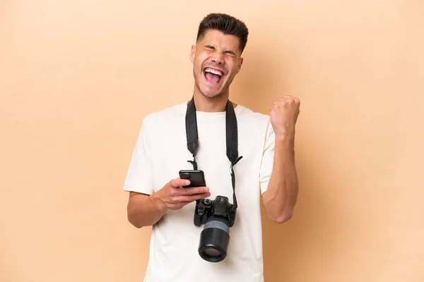 Jovem Fotógrafo Caucasiano Homem Isolado Fundo Bege Com Telefone Posição — Fotografia de Stock