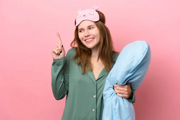 Young English woman in pajamas isolated on pink background in pajamas and intending to realizes the solution while lifting a finger up