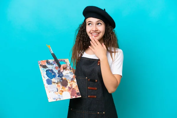 Młoda Artystka Arab Kobieta Trzyma Paletę Odizolowanych Niebieskim Tle Patrząc — Zdjęcie stockowe