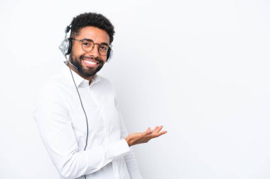 Tele pazarlamacı Brezilyalı bir adam beyaz arka planda izole edilmiş bir kulaklıkla çalışırken bir fikir sunuyor ve gülümsüyor.