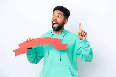 Genç Brezilyalı bir adam beyaz arka planda izole edilmiş boş bir levha tutuyor ve düşünüyor.