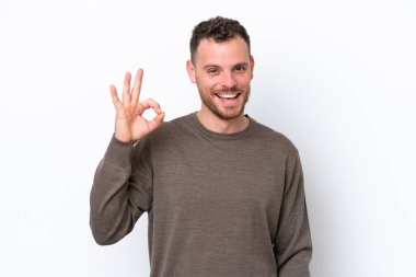 Beyaz arka planda izole edilmiş genç Brezilyalı adam parmaklarıyla tamam işareti gösteriyor