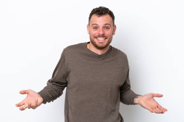 Genç Brezilyalı adam beyaz arka planda yalnız mutlu ve gülümsüyor.