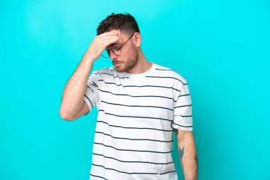 Mavi arka planda baş ağrısı olan genç Brezilyalı bir adam izole edilmiş.