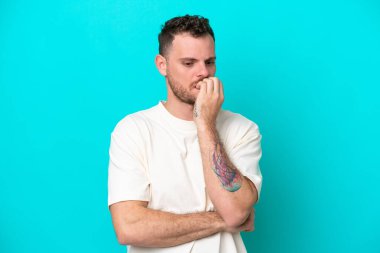 Mavi arka planda izole edilmiş genç Brezilyalı adamın şüpheleri var.