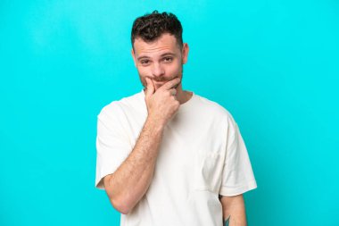 Mavi arka planda izole edilmiş genç Brezilyalı adamın şüpheleri var.