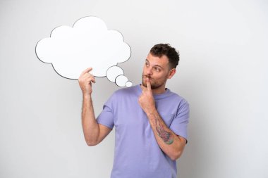 Düşünen bir konuşma balonu tutan Brezilyalı genç bir adam beyaz arka planda izole edilmiş.