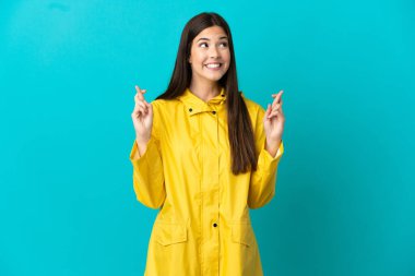 İzole edilmiş mavi arka planda yağmura dayanıklı ceket giyen Brezilyalı genç bir kız.