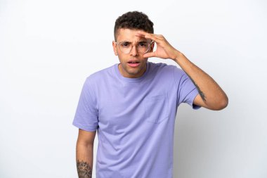 Beyaz arka planda izole edilmiş beyaz Brezilyalı genç bir adam bir şeye bakmak için çok uzaklara bakıyor.