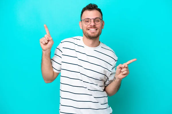 Jovem Brasileiro Isolado Fundo Azul Apontando Dedo Para Laterais Feliz — Fotografia de Stock