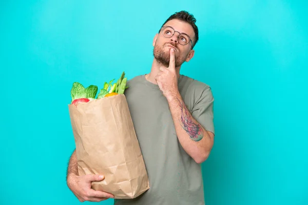 Young Brazilian Man Holding Grocery Shopping Bag Isolated Blue Background — Φωτογραφία Αρχείου