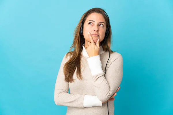 Jonge Telemarketer Vrouw Geïsoleerde Blauwe Achtergrond Met Twijfels Tijdens Het — Stockfoto