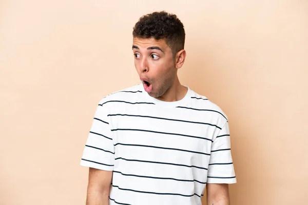 Young Brazilian Man Isolated Beige Background Doing Surprise Gesture While — Stok fotoğraf