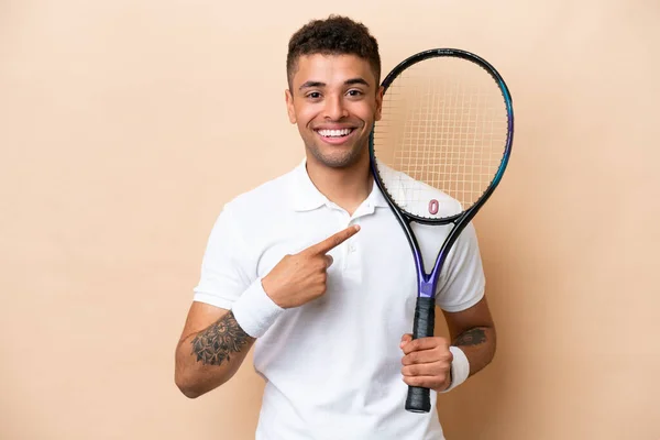 Молодий Вродливий Чоловік Грає Теніс Ізольований Бежевому Фоні Вказує Бік — стокове фото
