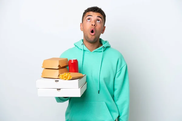 Young Brazilian Holding Fast Food Isolated White Background Looking Surprised — Φωτογραφία Αρχείου
