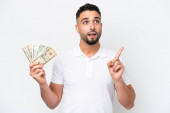 Young Arab man taking a lot of money isolated on white background thinking an idea pointing the finger up