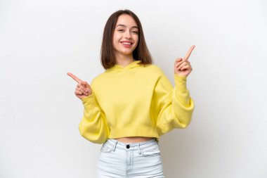 Beyaz arka planda izole edilmiş genç Ukraynalı kadın parmak uçlarını işaret ediyor ve mutlu