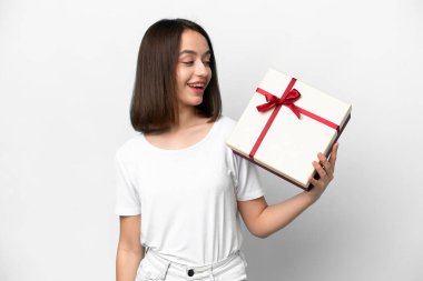 Genç Ukraynalı bir kadın elinde bir hediye tutuyor. Beyaz arka planda mutlu bir ifadeyle izole edilmiş.