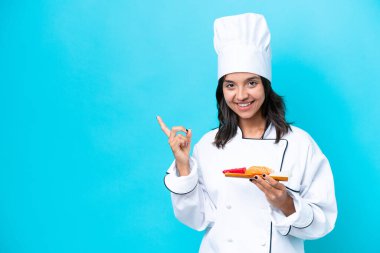 Genç İspanyol aşçı kadın elinde saşimi tutuyordu. Mavi arka planda izole edilmiş bir şekilde.