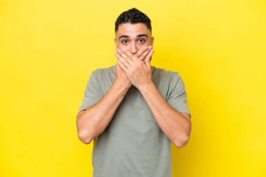 Young Arab handsome man isolated on yellow background covering mouth with hands